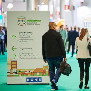 Visitors walking past sponsored signage at the UITP Summit.