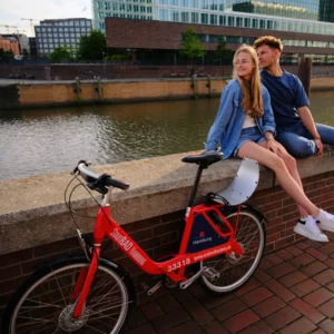 Couple siting on a wall with a shared bike. 